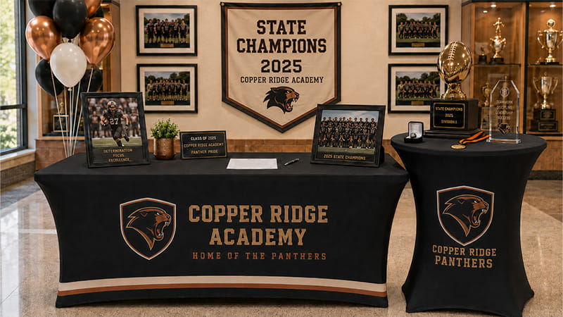 Signing Day display with matching stretch table covers, team photos, and championship awards