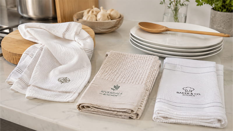 Kitchen towels with different weaves beside dishes and utensils