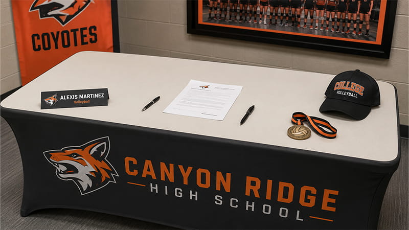 Signing Day table with documents, backup pens, athlete nameplate, college hat, and medal